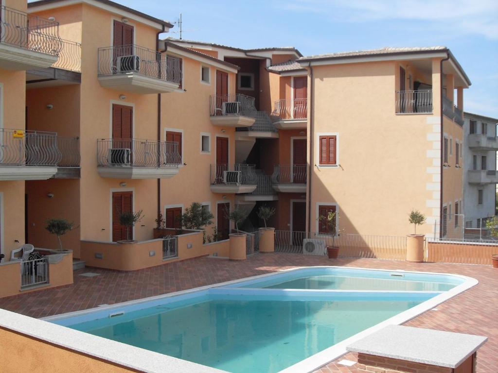 un appartement avec une piscine en face d'un bâtiment dans l'établissement Residenza I Gabbiani Valledoria, à Valledoria