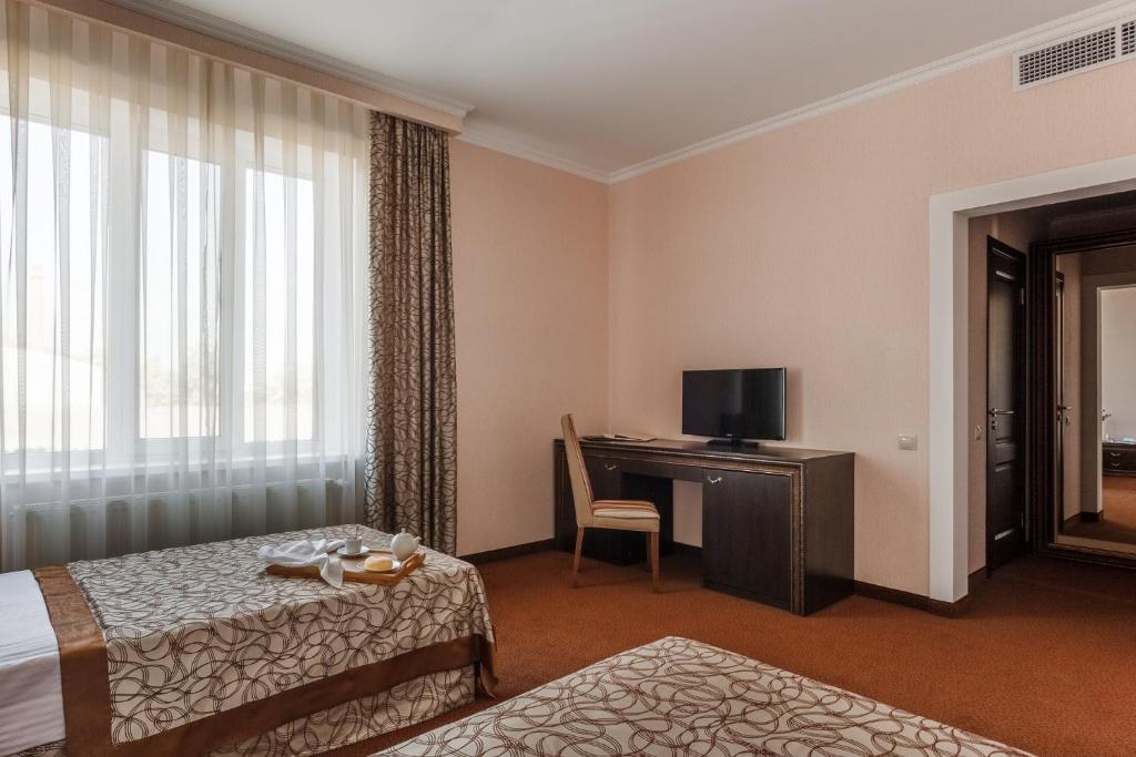 Habitación de hotel con cama, escritorio y TV. en Mask Hotel en Krasnodar