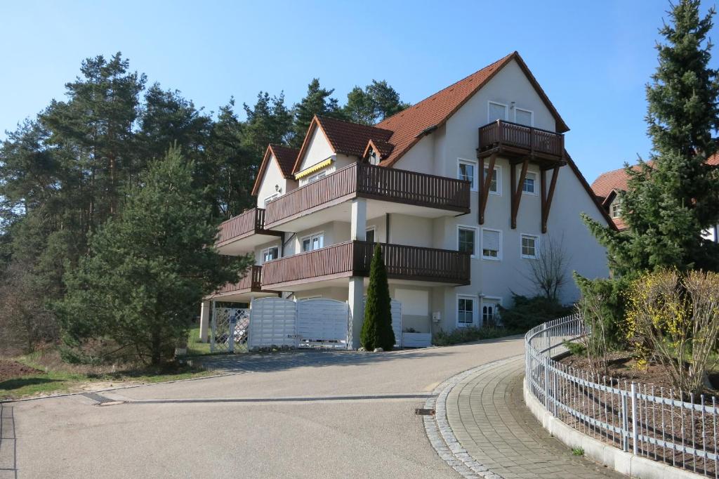 una gran casa blanca con una valla alrededor en Ferienwohnung Fränkisches Seenland - FeWo Antje, en Mitteleschenbach