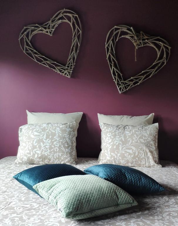 a bed with two hearts hanging on a purple wall at B&amp;B Aquavert &amp; Wellness in Tournai