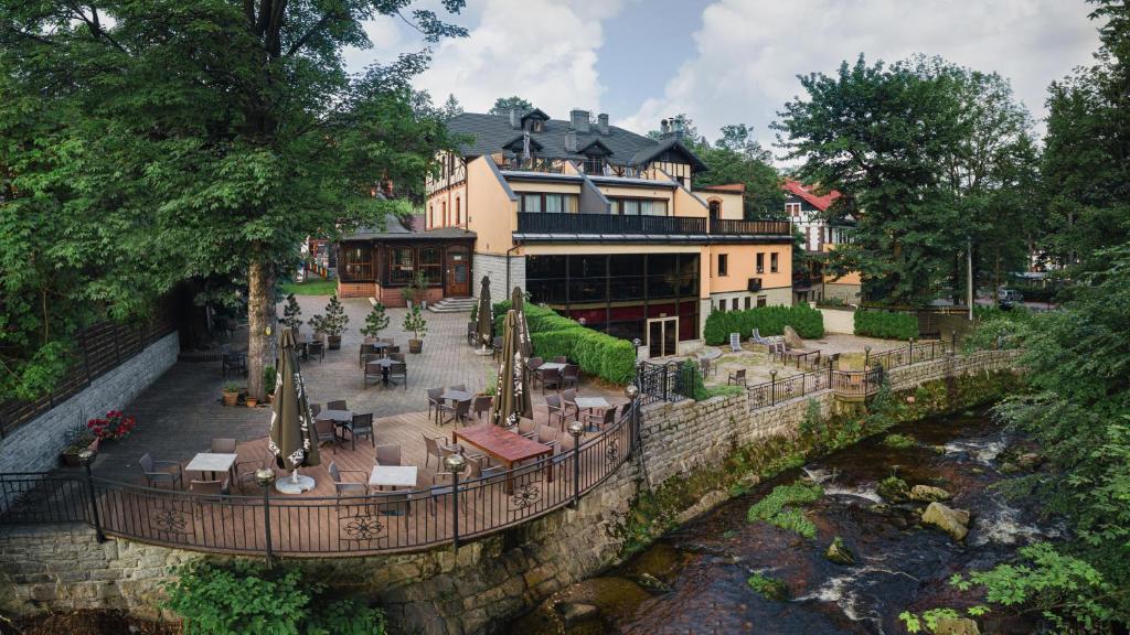 a building with tables and chairs next to a river at Willa 654 in Szklarska Poręba