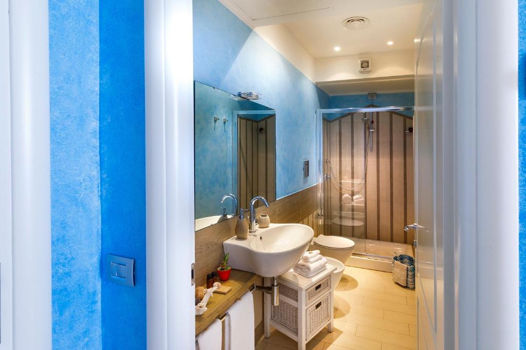 a blue bathroom with a sink and a toilet at Hotel La Villa Del Mare in Cagliari