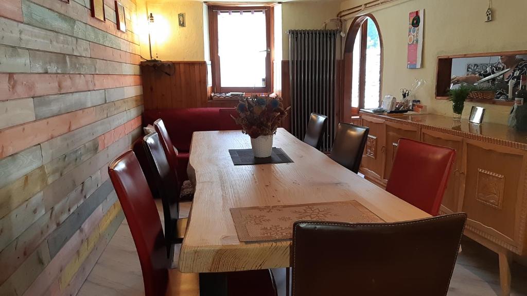 a wooden table with chairs and a vase of flowers on it at Baita Stampa in Chiesa in Valmalenco