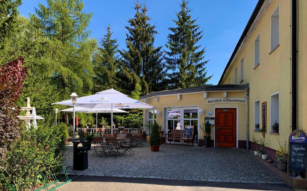 a patio with an umbrella and chairs and a building at Pension Am Waldguertel in Forst