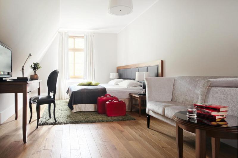 uma sala de estar com uma cama e uma mala vermelha em Hotel Zamek Lubliniec em Lubliniec