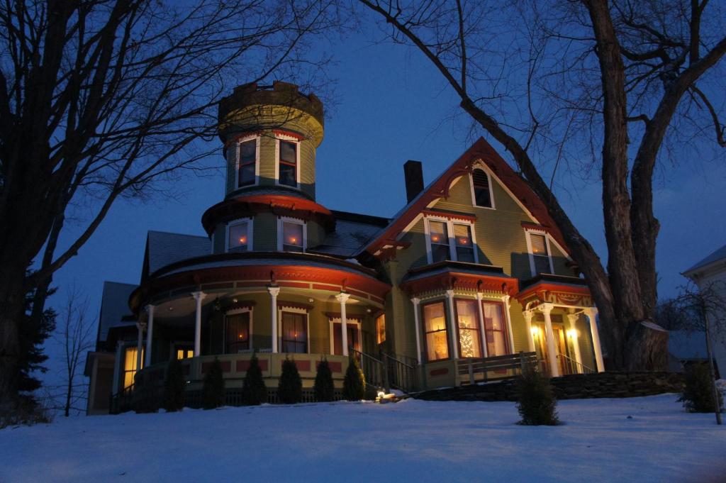 a large house in the snow at night at Maplecroft Bed & Breakfast in Barre
