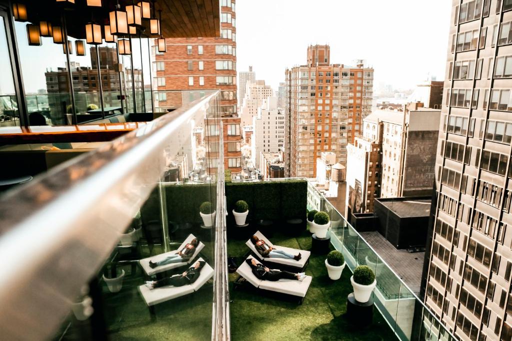 un balcón de un edificio con personas sentadas en sillas en citizenM New York Times Square, en Nueva York