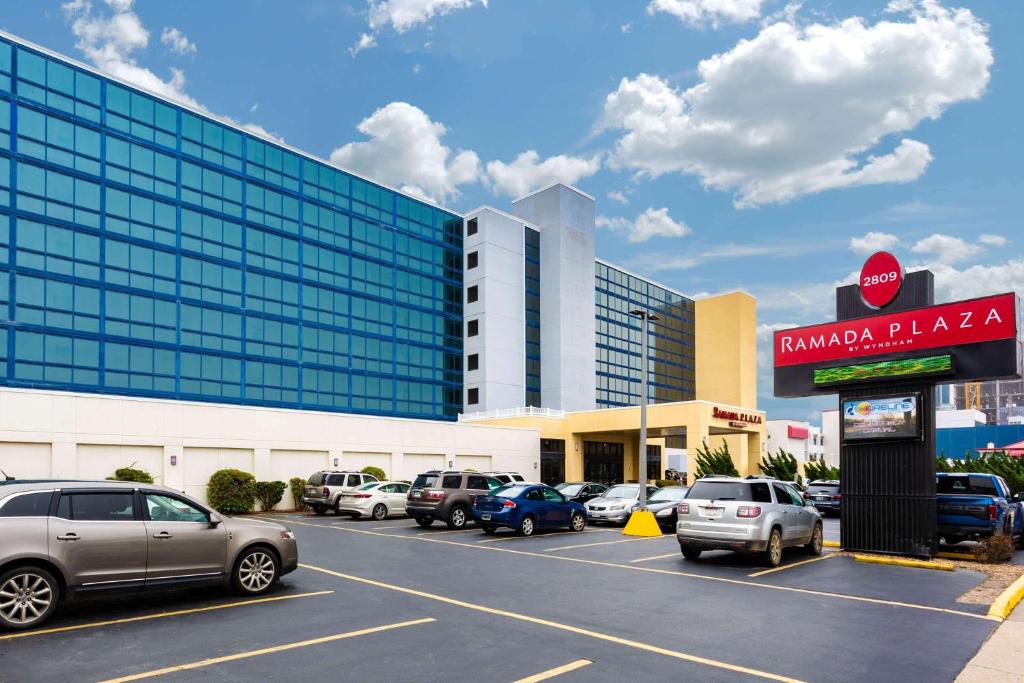 a parking lot with cars parked in front of a building at Ramada Plaza by Wyndham Virginia Beach Oceanfront in Virginia Beach