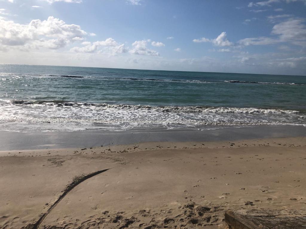 uma praia com o oceano e algumas pegadas na areia em Praia Carneiros Flat Hotel em Tamandaré