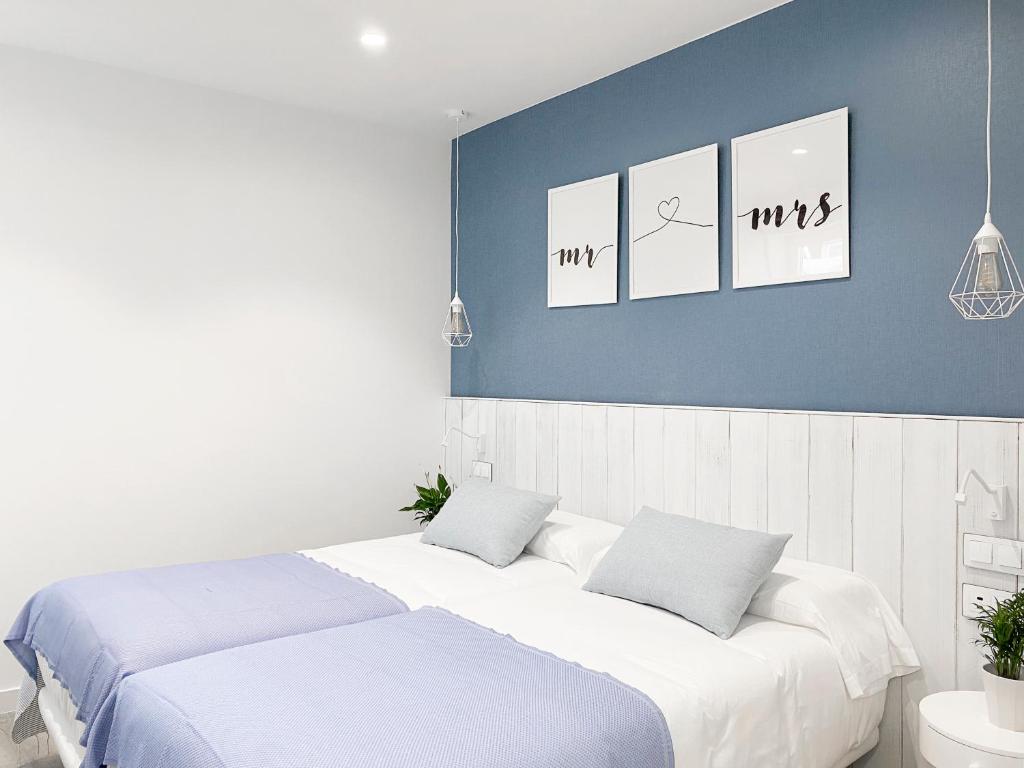 1 dormitorio con 2 camas y cuadros en la pared en Nerja Casual Rooms, en Nerja