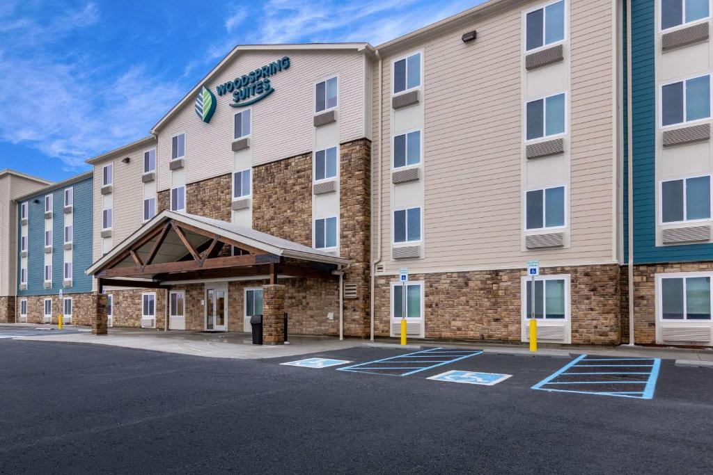 una representación de la parte delantera de un hotel con aparcamiento en WoodSpring Suites Indianapolis Airport South en Indianápolis