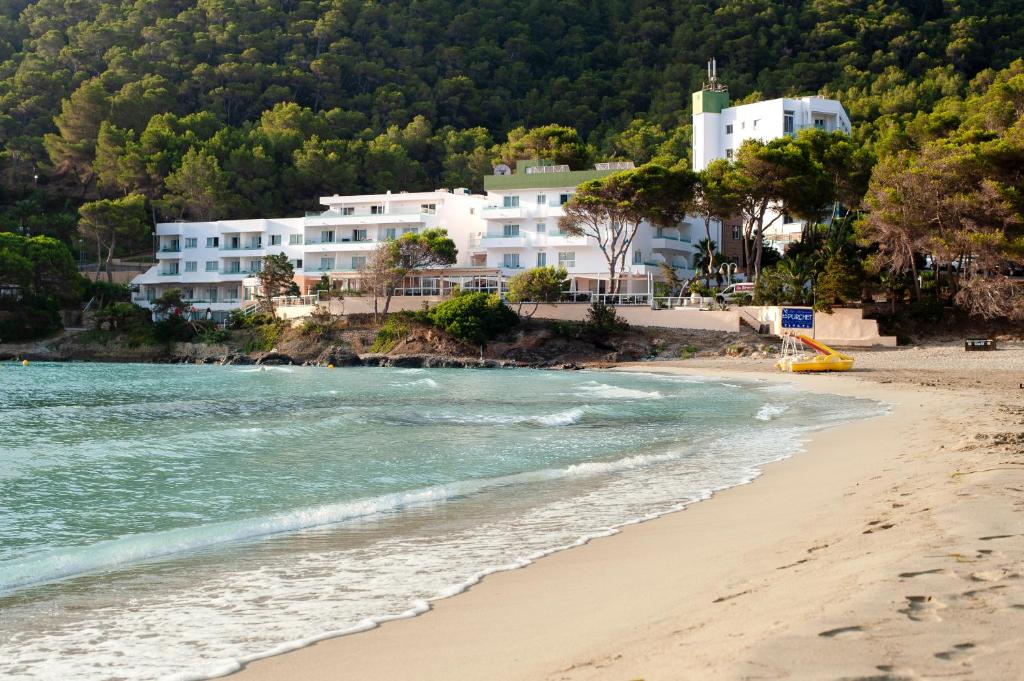 een uitzicht op een strand met gebouwen op de achtergrond bij Hotel El Pinar in Cala Llonga