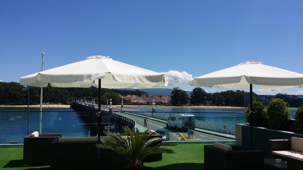 two white umbrellas sitting next to a body of water at Hotel Puente de La Toja in O Grove