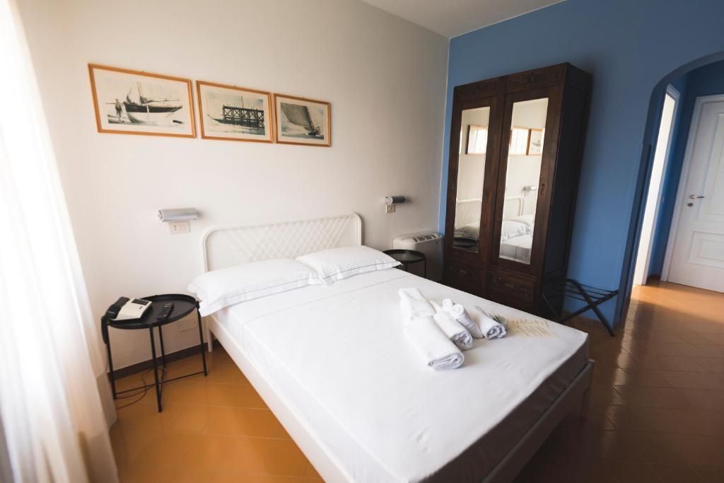 a bedroom with a white bed and a mirror at Mami Sabaudia Hotel in Sabaudia