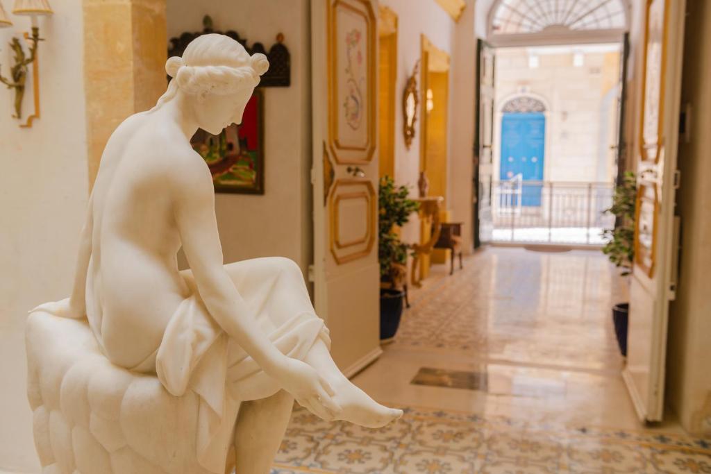 a statue of a woman sitting on a chair in a hallway at Casa Rocca Piccola B&B in Valletta