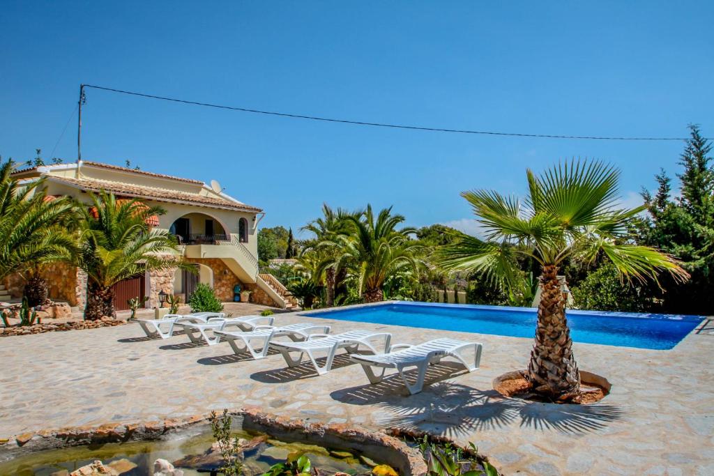 een zwembad met stoelen en een palmboom naast een resort bij Diana - pretty holiday property with garden and private pool in Benissa in Benissa
