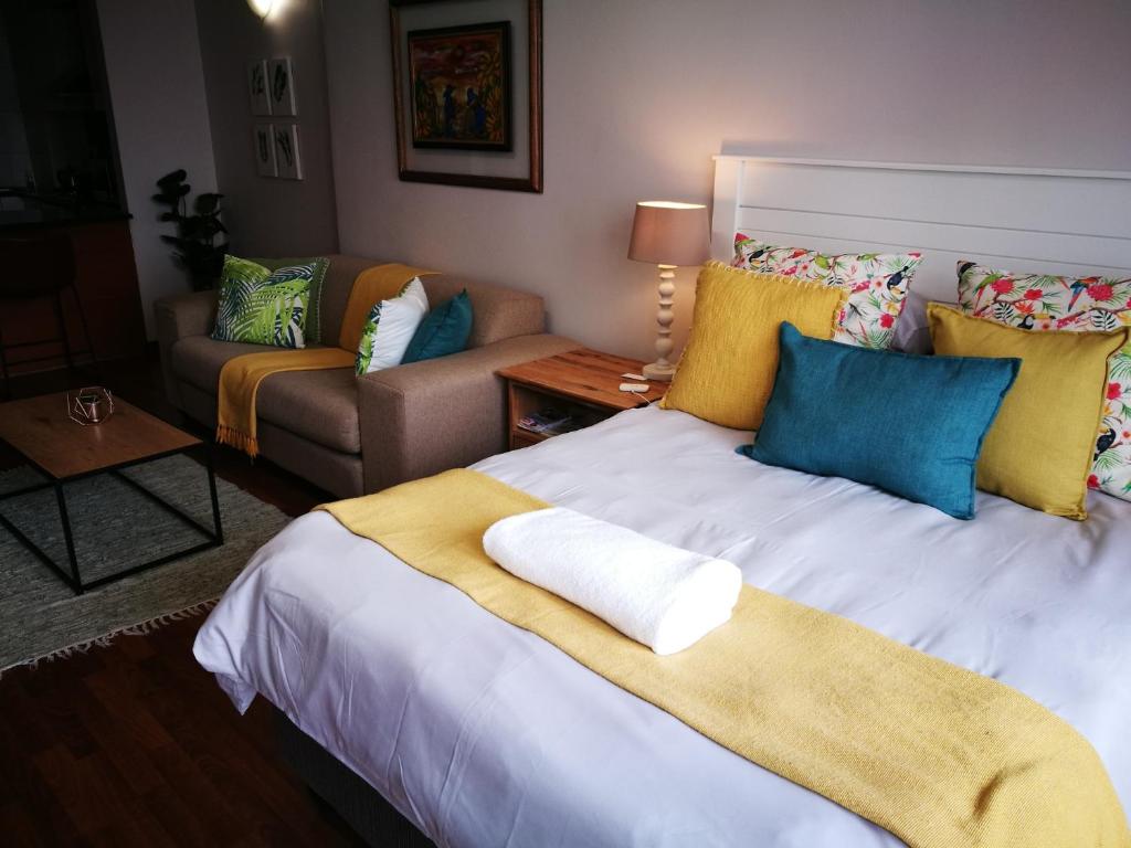 a bedroom with a large white bed with yellow and blue pillows at 45 Lighthouse Mall Apartment in Durban