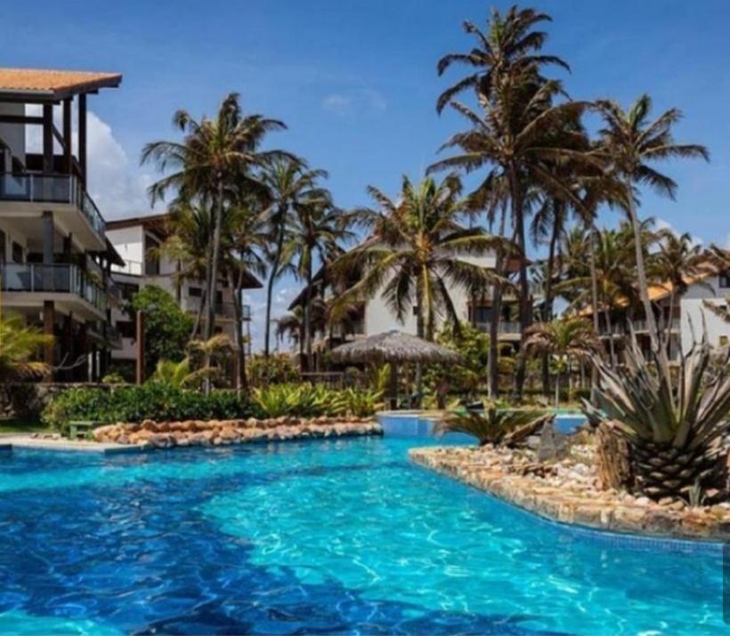 einen Pool in einem Resort mit Palmen in der Unterkunft Taibá Beach Resort Suítes in Taíba