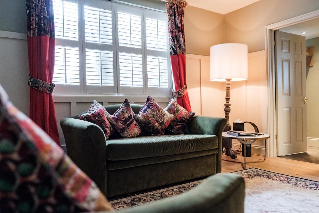 a living room with a green couch and a window at Wykeham Arms in Winchester