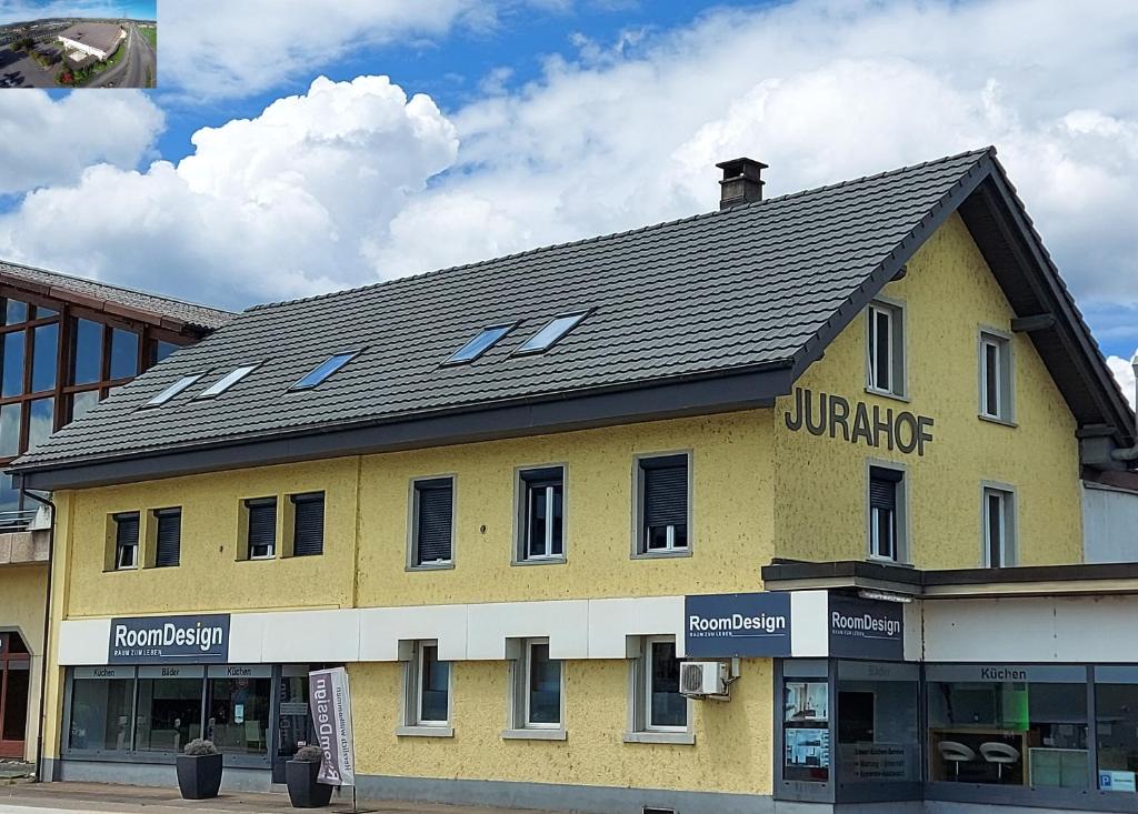 un gran edificio amarillo con techo negro en Appartamenti Jurahof, en Däniken
