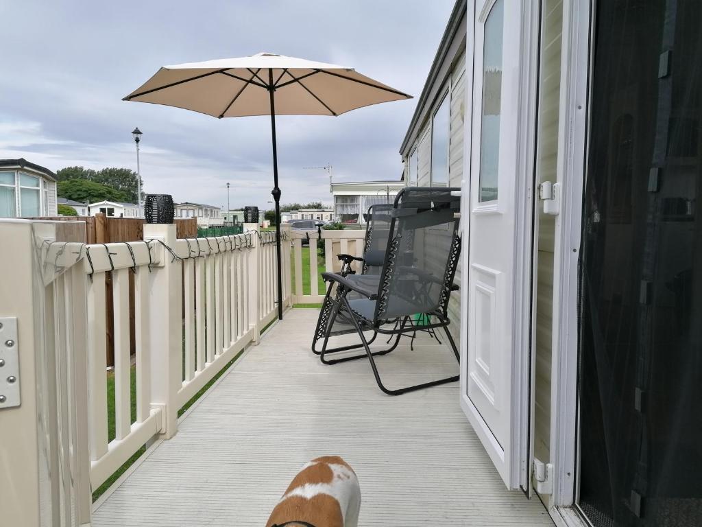 a person is standing on a porch with an umbrella at Sunshine Lodge-by-Saltfleet - 221 Kingfisher Gardens in Saltfleet