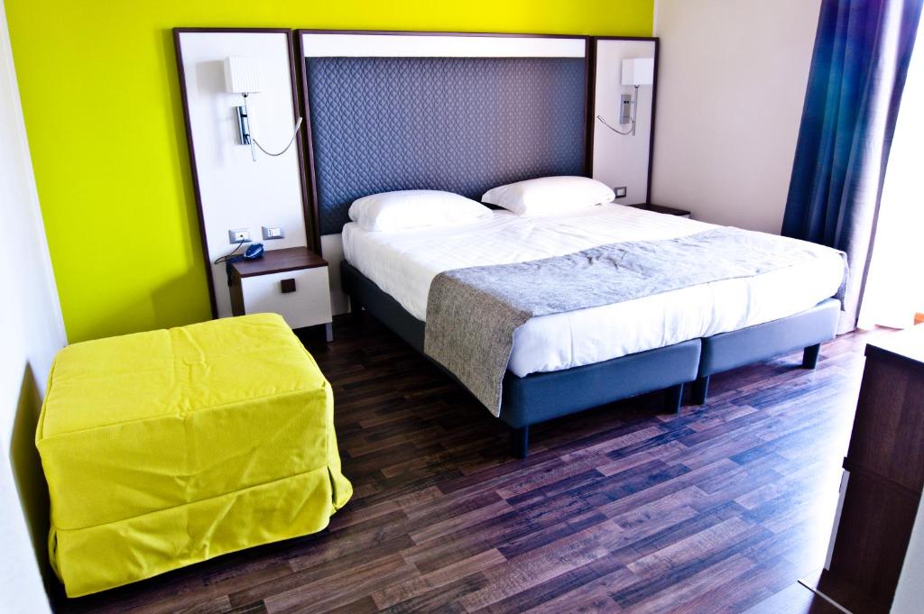 a bedroom with a bed and a yellow wall at Hotel Gasparina in Castelnuovo del Garda