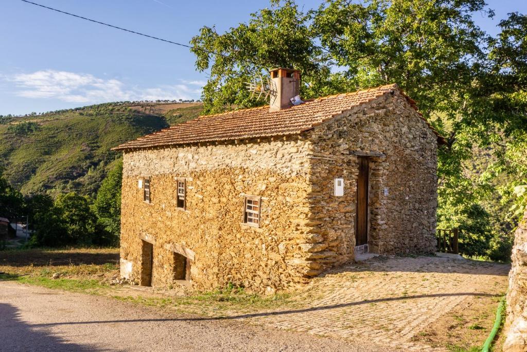 Negreda的住宿－Casa da Corriça - Alojamento Local，一座古老的石头建筑,在路边有一扇门