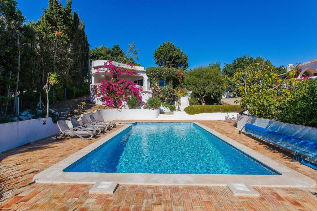 a swimming pool with chairs and a house at Casa dos Gemeos in Luz