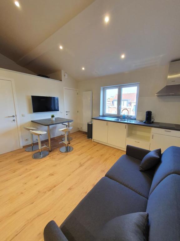 a living room with a blue couch and a table at Brussels North - Pajot Apartments in Wemmel