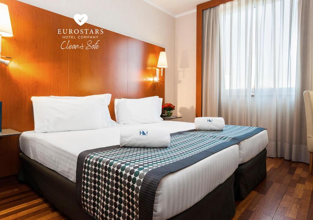 a hotel room with a large bed with white pillows at Eurostars Toscana in Lucca