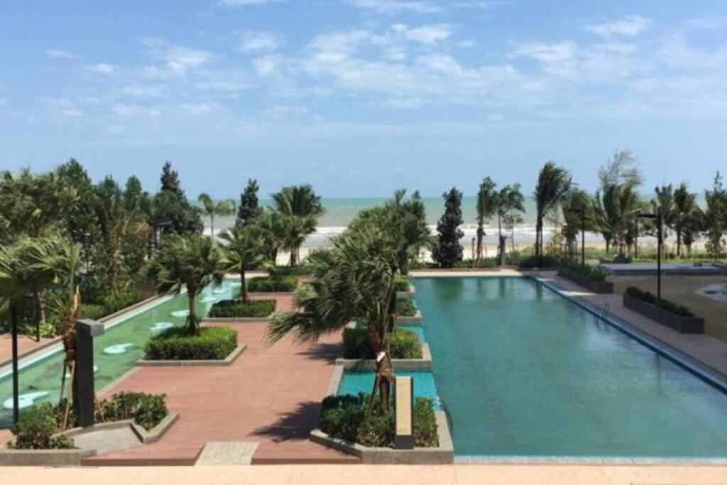 - une grande piscine bordée de palmiers et une plage dans l'établissement OPAHOME@ Timurbay Seafront Residence 2BR Family suite Seaview and Poolview, à Kuantan