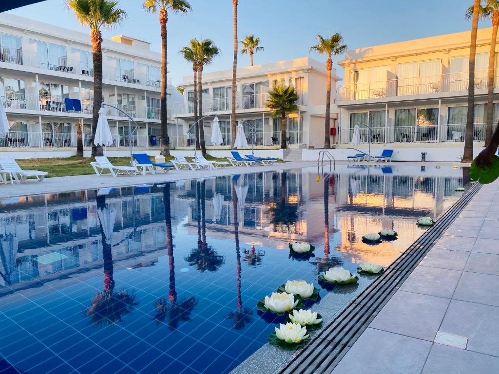 a pool at a hotel with chairs and palm trees at Lysithea Hotel in Larnaka