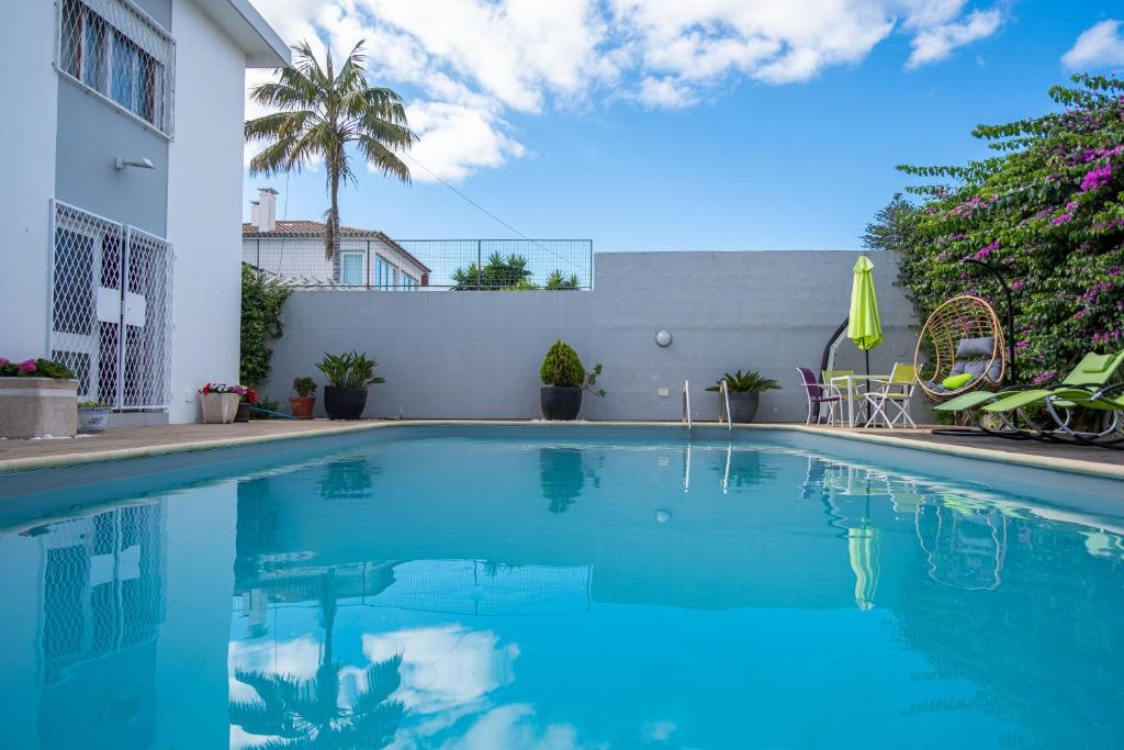 a swimming pool with blue water in front of a building at Snooker House in Ponta Delgada