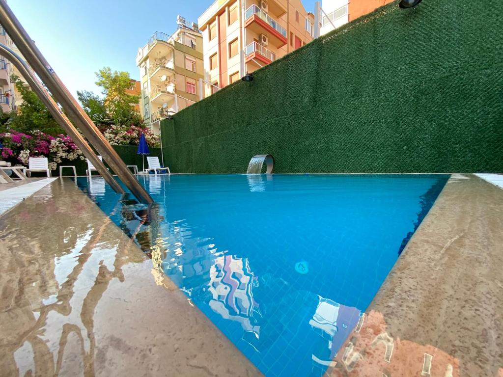 einem Pool mit Reflexion im Wasser in der Unterkunft LONDON OTEL in Antalya