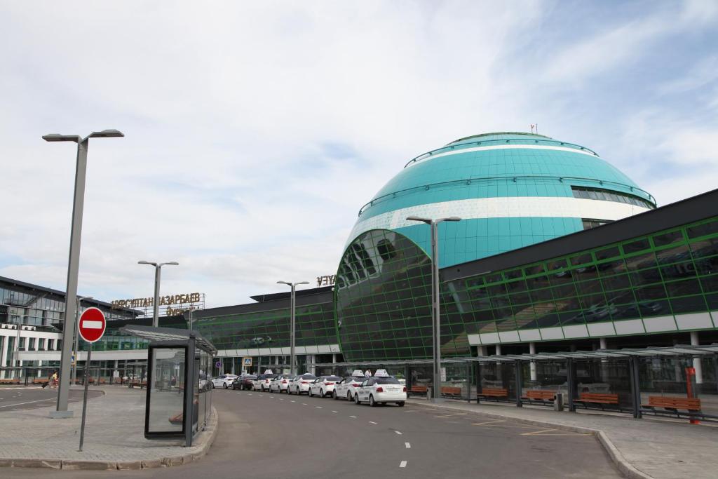a large building with cars parked in a parking lot at PORT INN Hotel in Astana