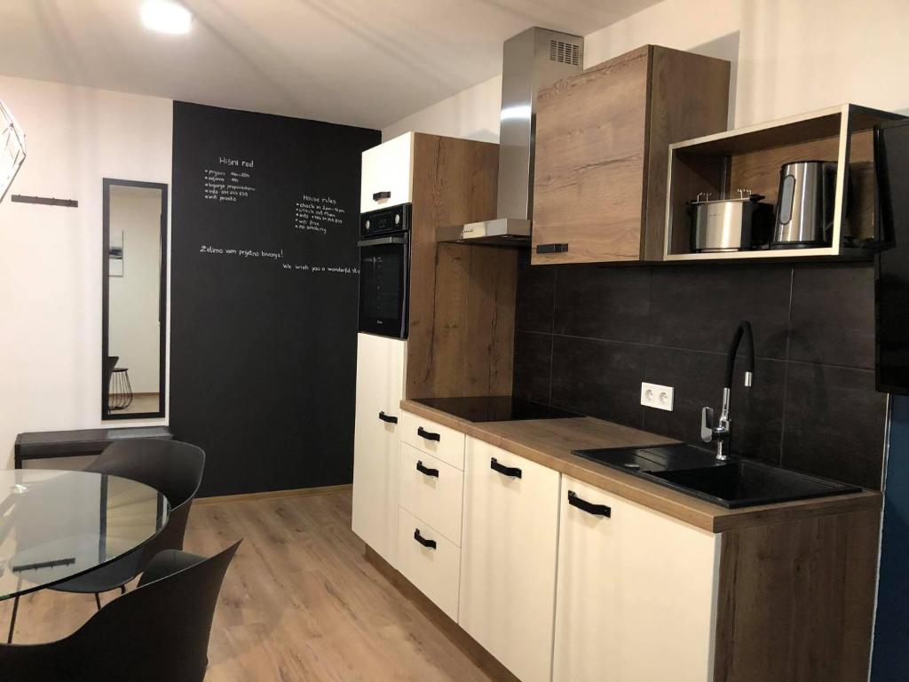 een keuken met witte kasten en een zwarte muur bij Apartment Šelih in Maribor
