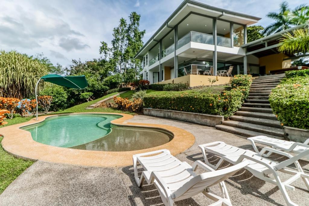 ein Haus mit Pool und Stühlen davor in der Unterkunft Casa Cariblanco in Tarcoles