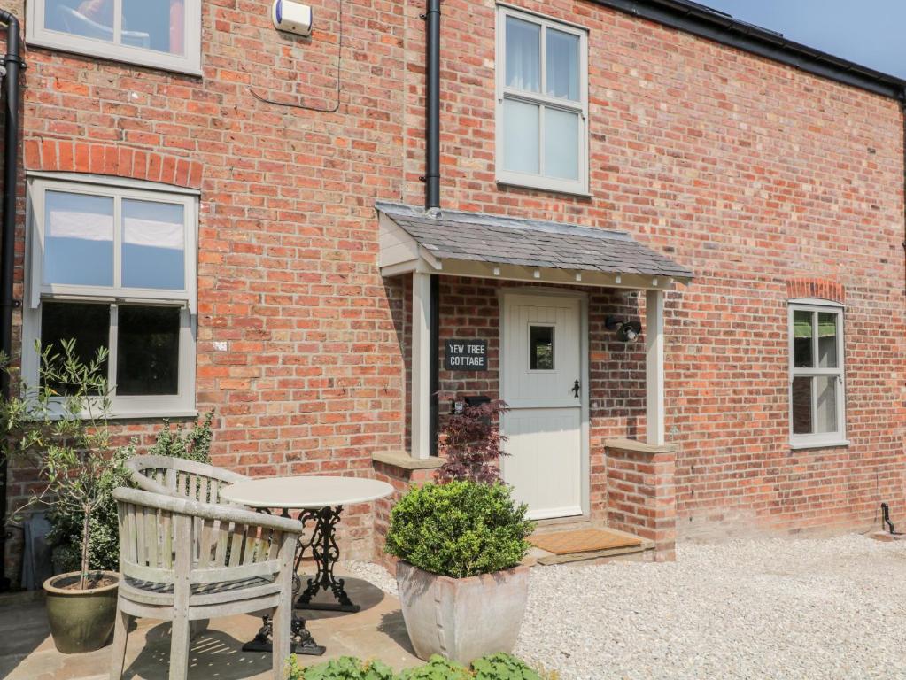 a brick house with a table and a bench in front of it at Yew Tree Cottage in York