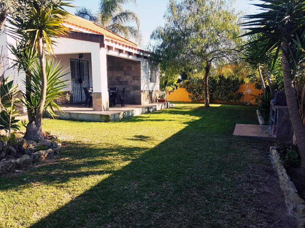um quintal de uma casa com palmeiras em Chalet la Huerta 2 amplios jardines y WiFi em Conil de la Frontera