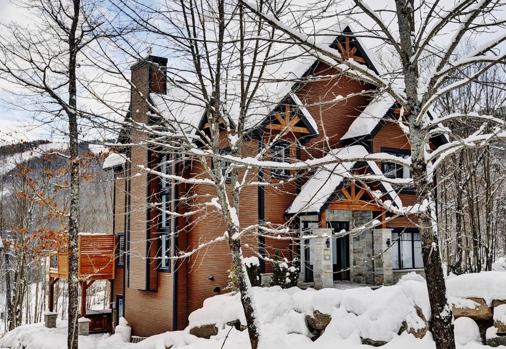 a house covered in snow in front at Chalet 30 Chemin des Skieurs by Chalets Alpins in Stoneham
