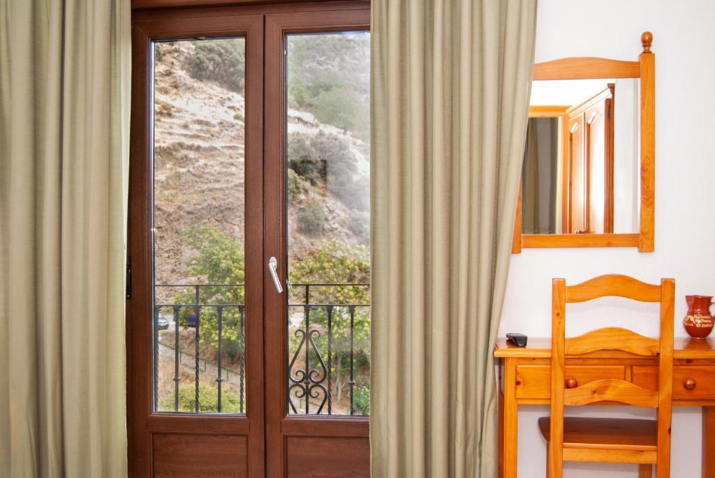 Habitación con puerta y vistas a un balcón. en Hostal Mulhacen, en Trevélez