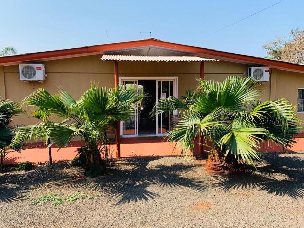 une maison avec des palmiers devant elle dans l'établissement Repouso do Tchê, à Foz do Iguaçu