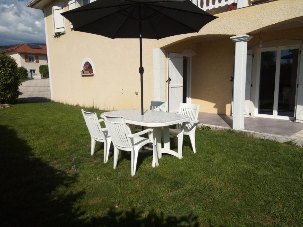 - une table et des chaises avec un parasol sur la cour dans l'établissement Studio indépendant 40m² avec jardin privé, à Hauteville-Lompnes