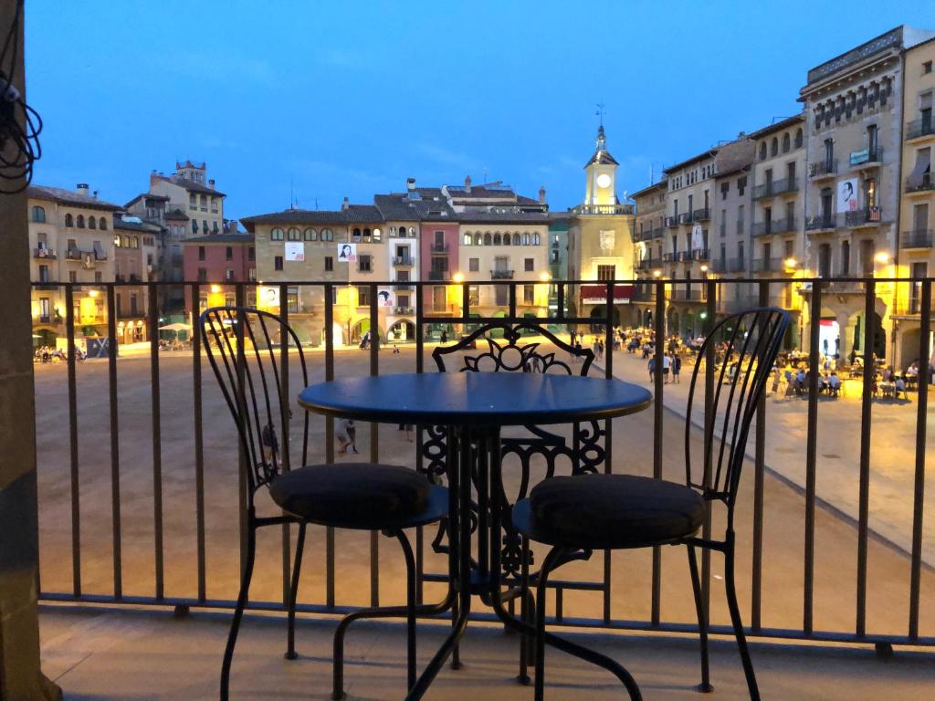 a table and chairs on a balcony with a view of a city at Apartaments Vicus 3 con vistas a la Plaza Mayor de Vic in Vic