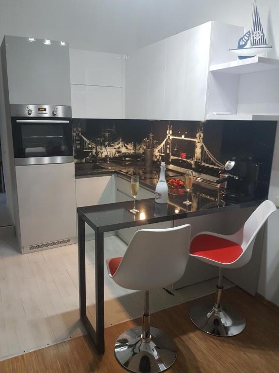 eine Küche mit einem schwarzen Tisch und 2 weißen Stühlen in der Unterkunft London Apartment, Odessa in Odessa