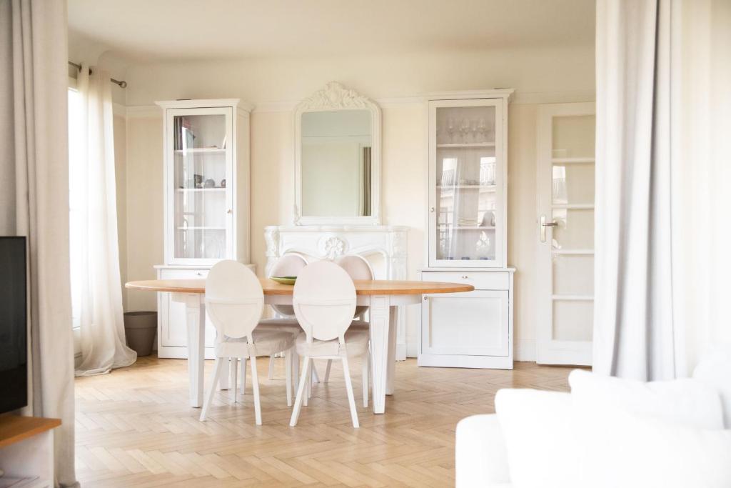 een witte keuken met een houten tafel en witte stoelen bij Romantic Nest in Parijs