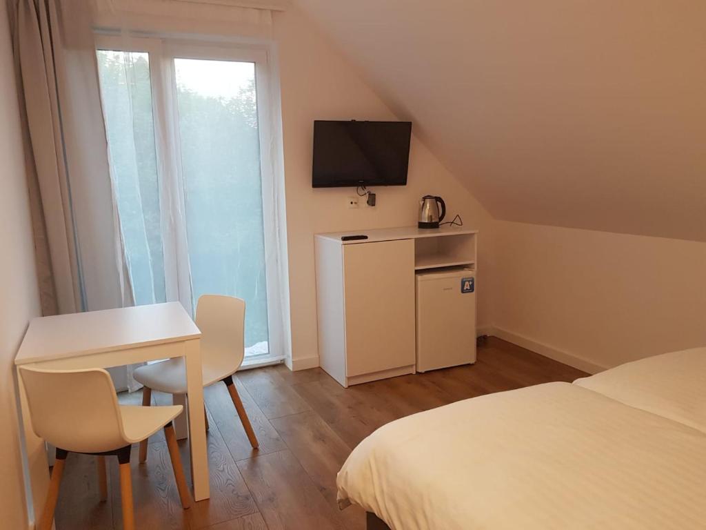 Kleines Zimmer mit einem Tisch, einem Bett und einem TV. in der Unterkunft Pensjonat Orle Gniazdo in Jelenia Góra
