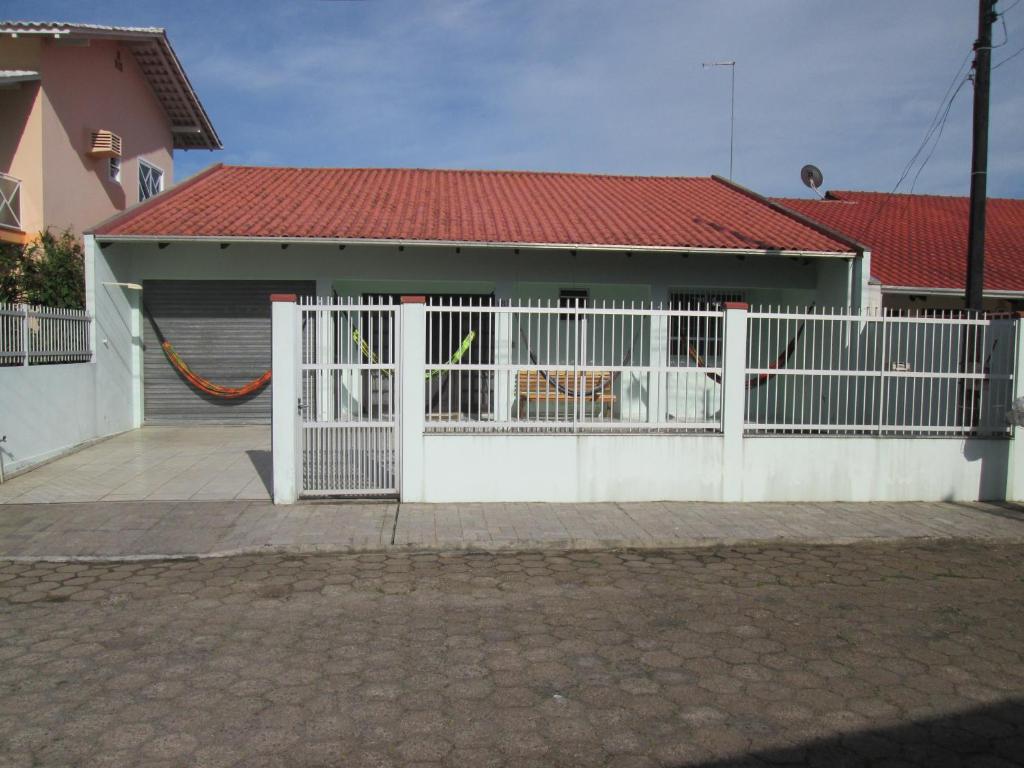 una cerca blanca frente a una casa en alugo esta linda e bem equipada casa em penha sc perto do beto carrero e da praia, en Penha
