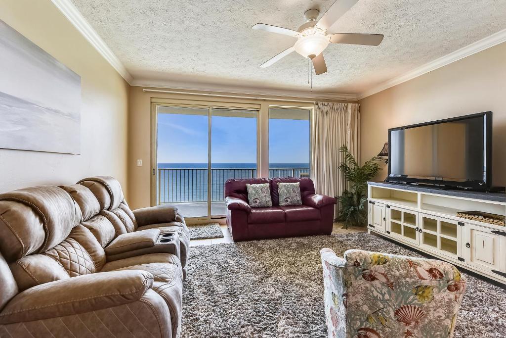 a living room with a television and a couch and chairs at Treasure Island 2103 in Panama City Beach