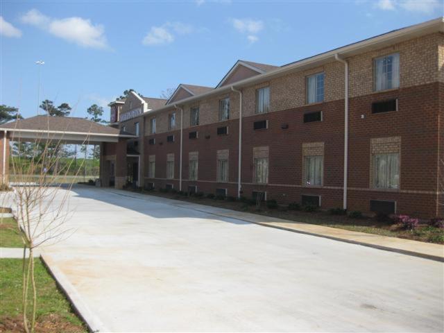 a large brick building with a sidewalk in front of it at Heritage Inn in Picayune